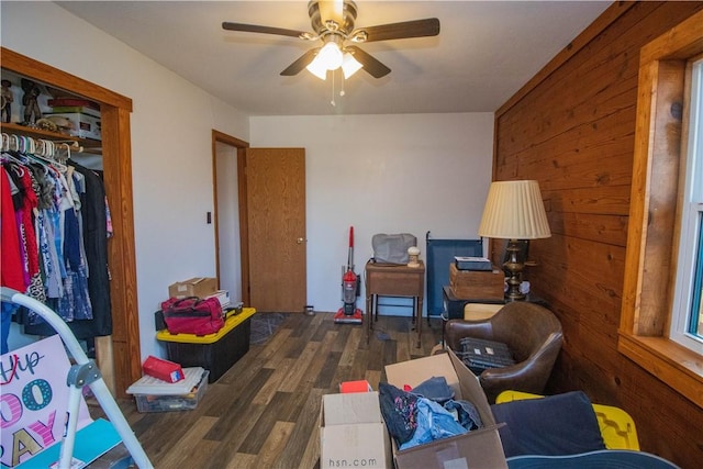 bedroom with dark wood-type flooring, wooden walls, and ceiling fan