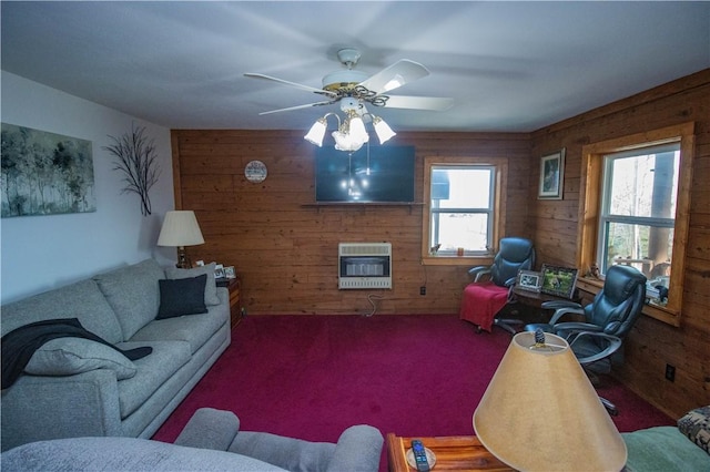 living room featuring heating unit, a fireplace, wooden walls, carpet flooring, and ceiling fan