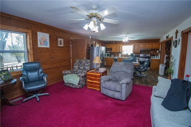 living room with ceiling fan and wood walls