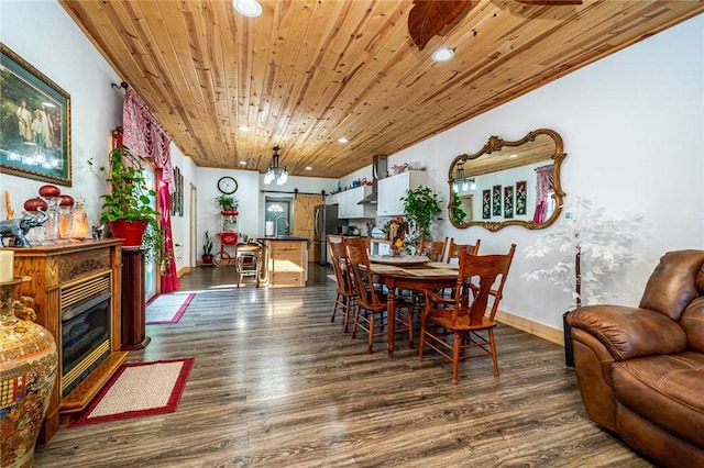 dining area featuring dark hardwood / wood-style flooring, wooden ceiling, and a barn door