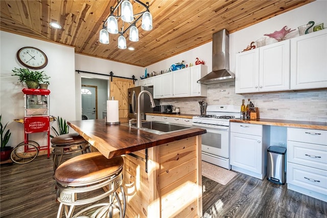 kitchen featuring white cabinetry, wall chimney range hood, a barn door, and white gas range