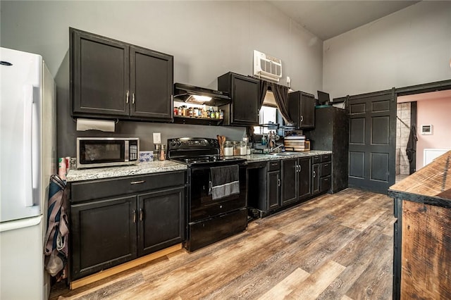 kitchen with sink, light hardwood / wood-style flooring, white refrigerator, black / electric stove, and a barn door