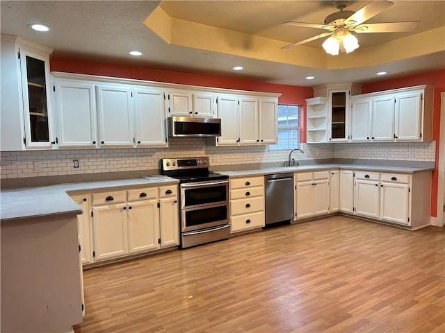 kitchen featuring a raised ceiling, appliances with stainless steel finishes, and white cabinets