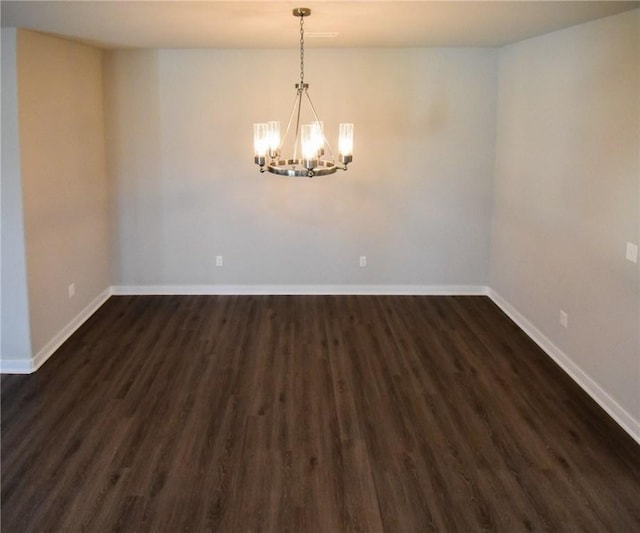 spare room with an inviting chandelier and dark hardwood / wood-style floors