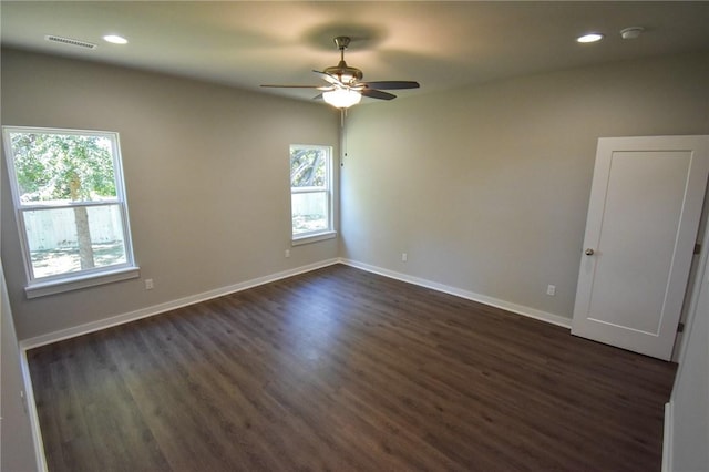 spare room featuring ceiling fan, dark wood-type flooring, and a healthy amount of sunlight