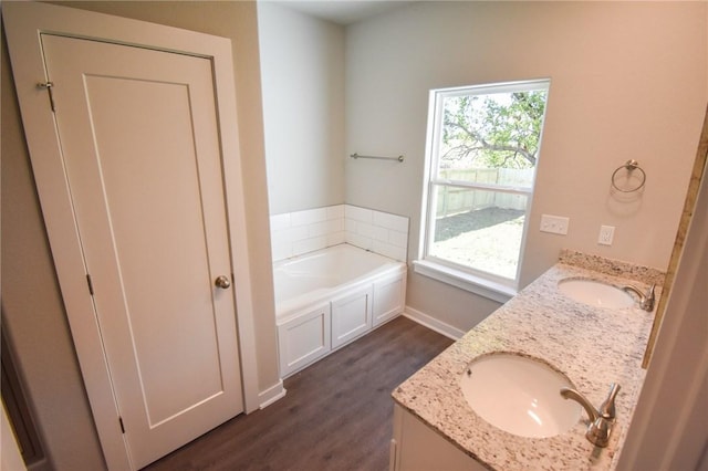 bathroom with a tub to relax in, wood-type flooring, and vanity