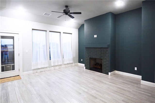 unfurnished living room featuring ceiling fan, a fireplace, vaulted ceiling, and light hardwood / wood-style flooring