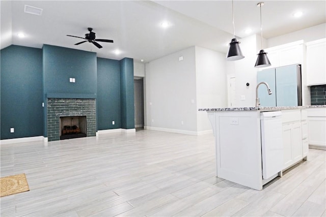 kitchen with pendant lighting, stainless steel fridge, white dishwasher, an island with sink, and white cabinets