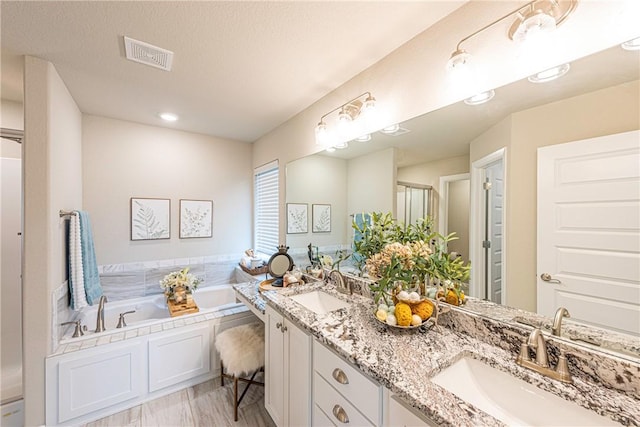 bathroom with vanity, a textured ceiling, and a tub