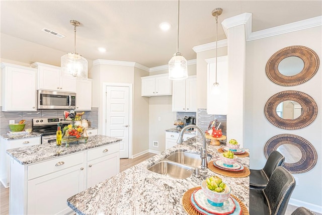 kitchen with stainless steel appliances, white cabinetry, sink, and decorative light fixtures