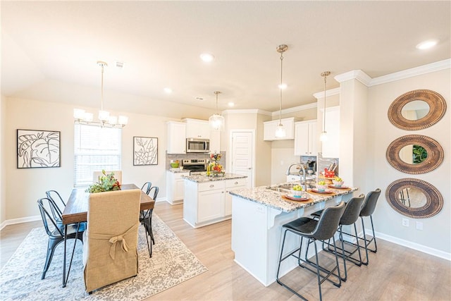 kitchen featuring sink, kitchen peninsula, stainless steel appliances, light stone countertops, and white cabinets