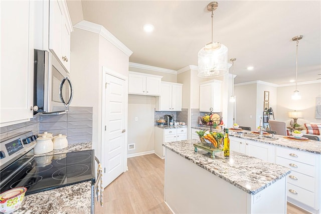 kitchen featuring stainless steel appliances, a kitchen island, white cabinets, and decorative light fixtures