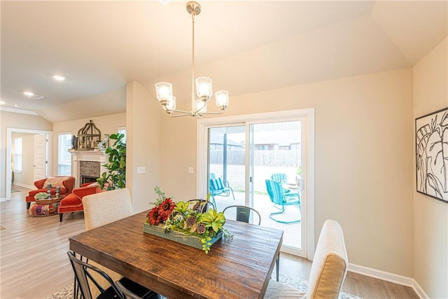 dining area with vaulted ceiling, plenty of natural light, an inviting chandelier, and light hardwood / wood-style floors