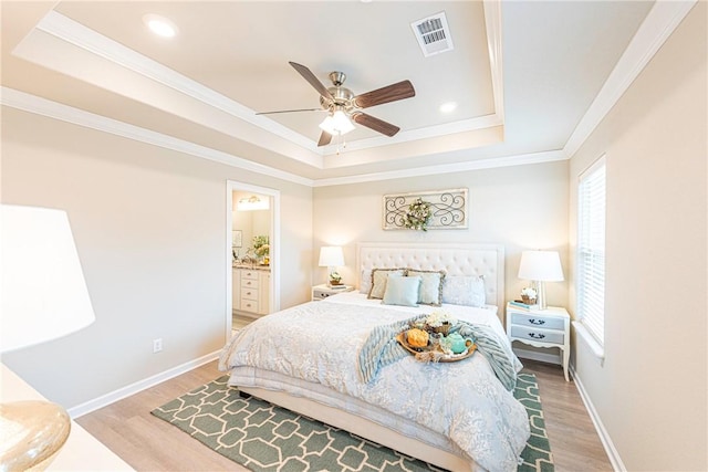 bedroom featuring ensuite bathroom, crown molding, a raised ceiling, ceiling fan, and hardwood / wood-style floors