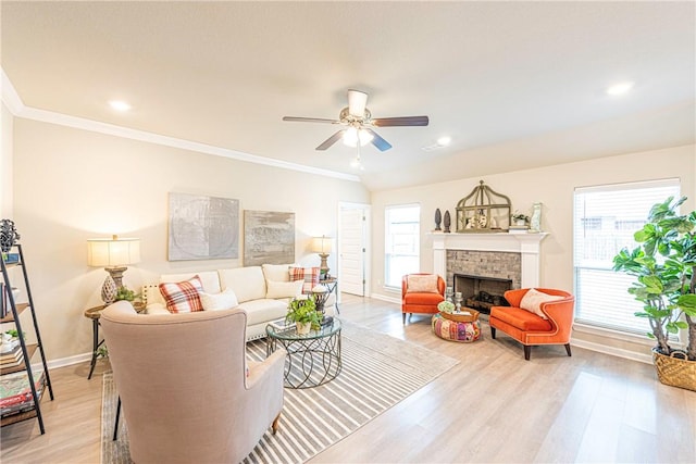 living room featuring crown molding, a brick fireplace, a healthy amount of sunlight, and light wood-type flooring