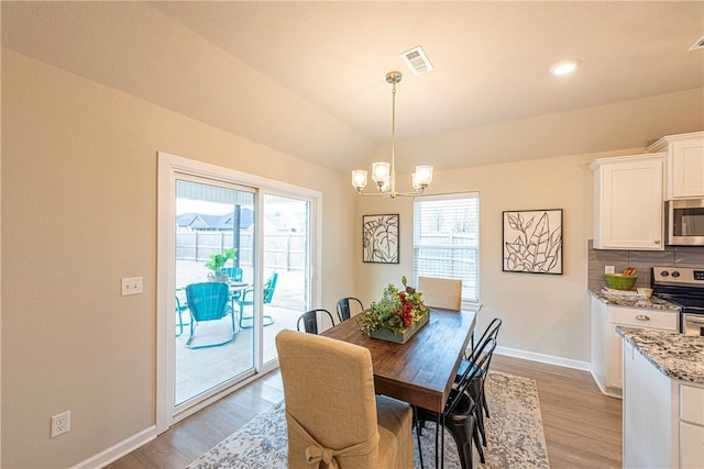 dining room with an inviting chandelier, a wealth of natural light, and light hardwood / wood-style floors