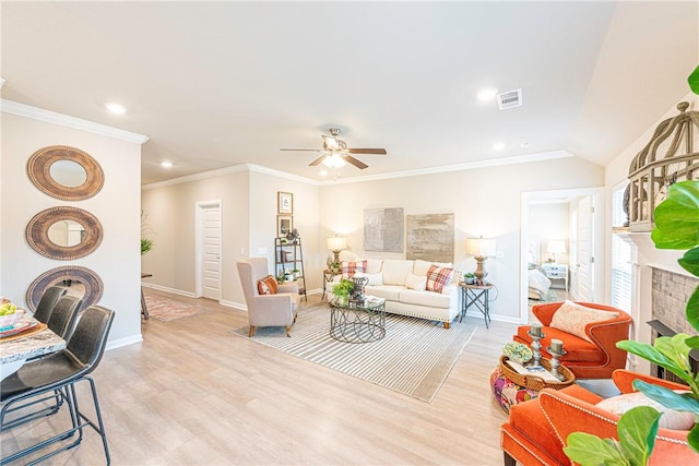 living room with a tiled fireplace, ornamental molding, ceiling fan, and light wood-type flooring