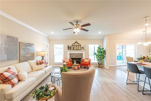 living room featuring ornamental molding, ceiling fan with notable chandelier, plenty of natural light, and light hardwood / wood-style floors