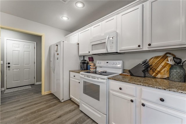 kitchen with white appliances, dark stone counters, light wood-type flooring, and white cabinets