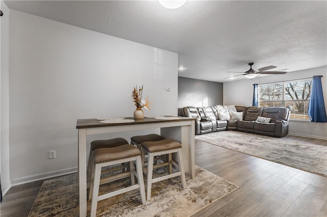 living room featuring wood-type flooring, a textured ceiling, and ceiling fan