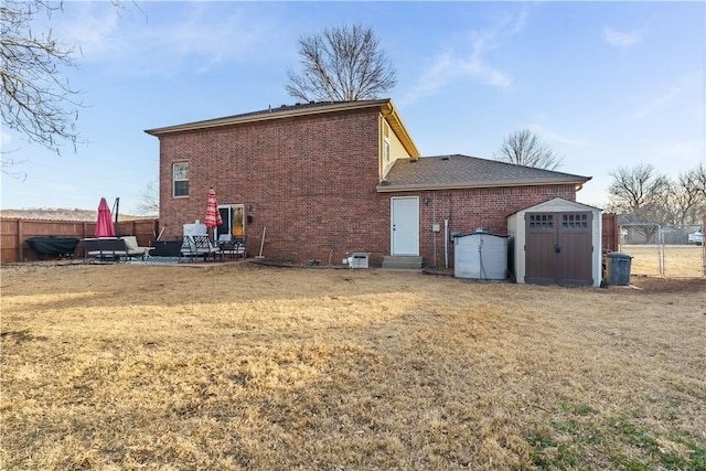 rear view of property with a yard, a patio area, and a storage unit