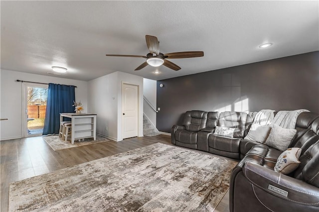 living room featuring dark wood-type flooring, a textured ceiling, and ceiling fan