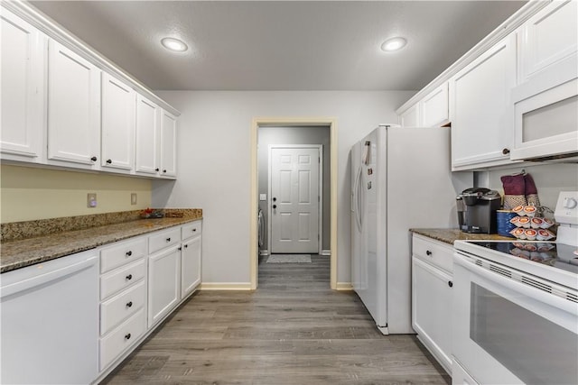 kitchen featuring dark stone countertops, white cabinets, and white appliances