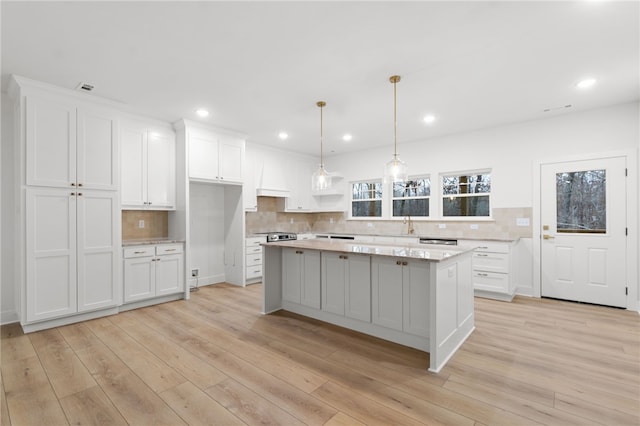 kitchen featuring light wood-type flooring, a kitchen island, and white cabinetry