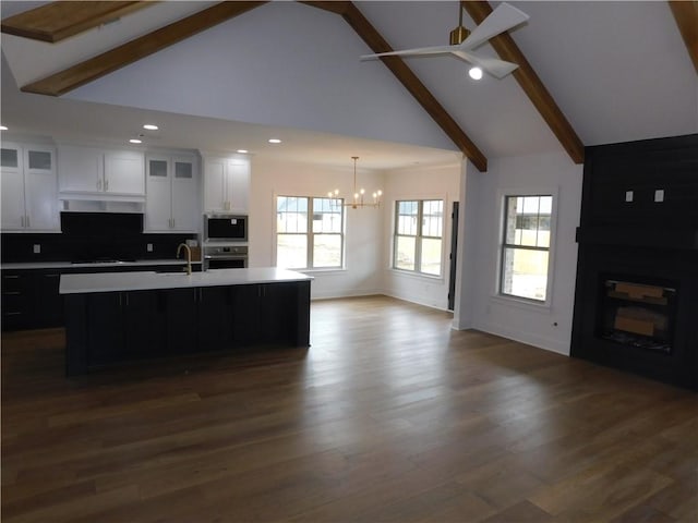 kitchen featuring stainless steel appliances, white cabinetry, a kitchen island with sink, and a large fireplace