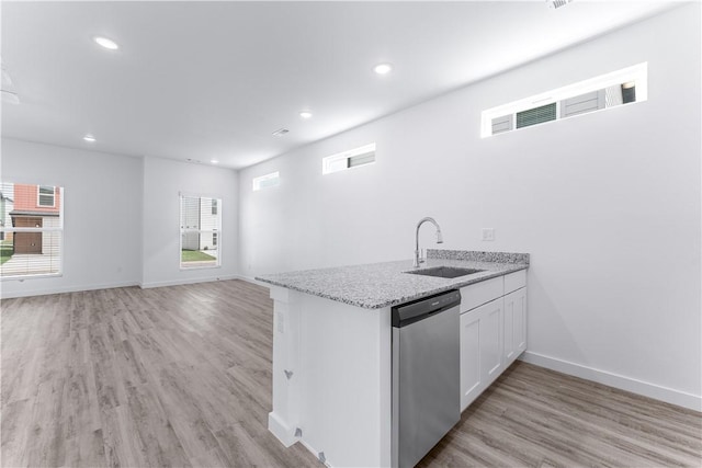 kitchen featuring sink, white cabinetry, light stone counters, light wood-type flooring, and dishwasher