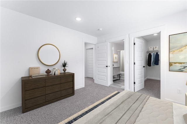 bedroom featuring ensuite bathroom, a walk in closet, and light carpet