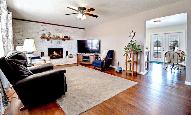 3001 Waukesha Rd, Siloam Springs, AR 72761 - living area featuring a ceiling fan, wood finished floors, a brick fireplace, baseboards, and a textured ceiling