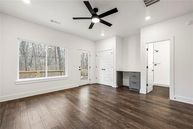 unfurnished bedroom with built in desk, dark wood-type flooring, access to outside, and ceiling fan