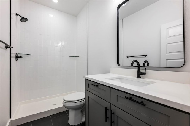 bathroom featuring vanity, toilet, tile patterned flooring, and a tile shower