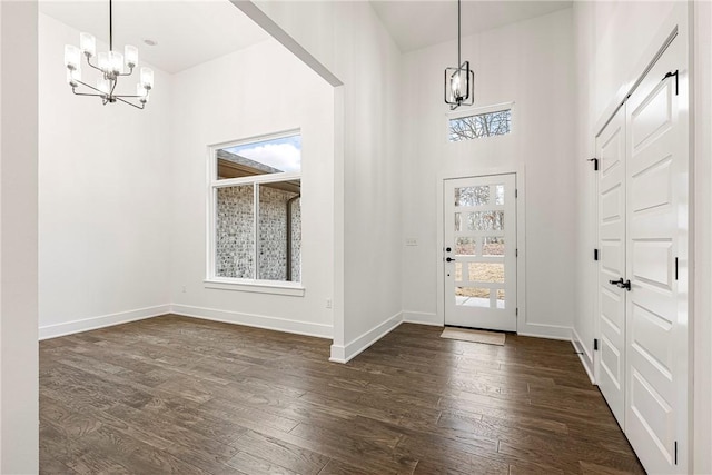 foyer featuring a notable chandelier, a towering ceiling, and dark wood-type flooring