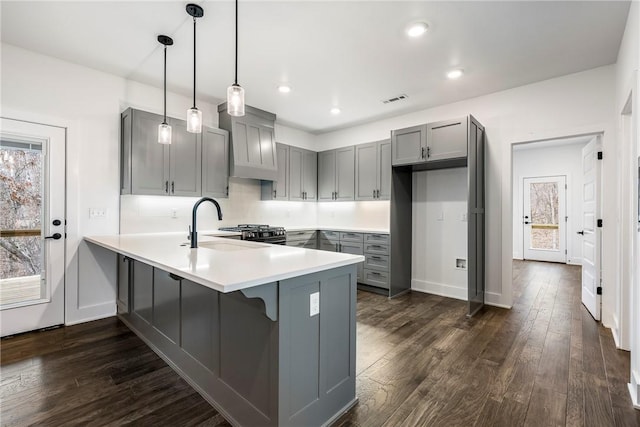 kitchen with dark wood-type flooring, sink, decorative light fixtures, gray cabinets, and kitchen peninsula