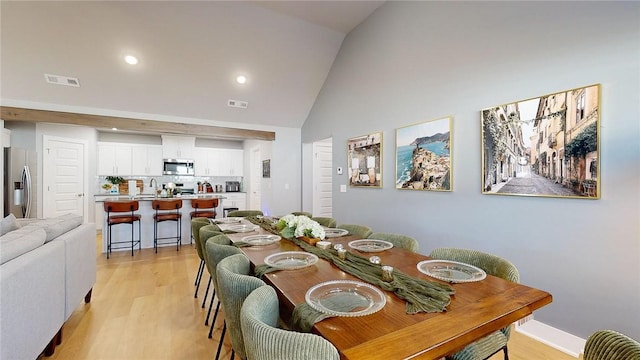 dining space with high vaulted ceiling, sink, and light hardwood / wood-style floors