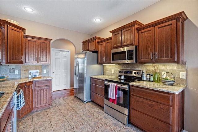 kitchen featuring light stone counters, light tile patterned floors, backsplash, and stainless steel appliances