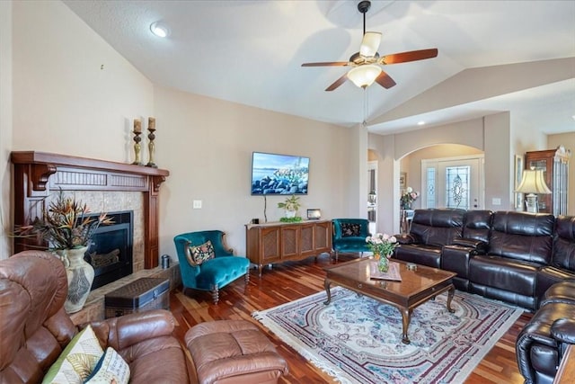 living room featuring hardwood / wood-style flooring, vaulted ceiling, ceiling fan, and a fireplace