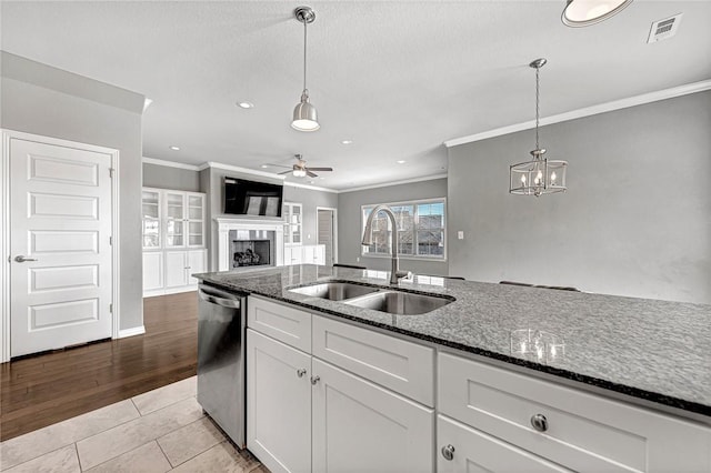 kitchen with pendant lighting, sink, dishwasher, white cabinetry, and dark stone counters