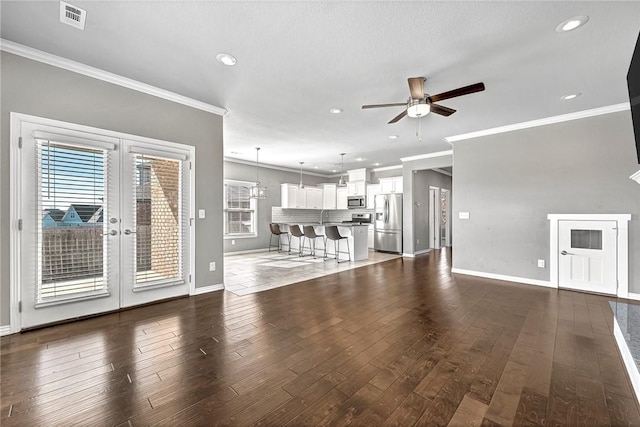 unfurnished living room featuring ornamental molding, dark wood-type flooring, ceiling fan, and french doors