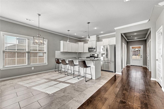 kitchen with white cabinetry, decorative light fixtures, a breakfast bar, and appliances with stainless steel finishes