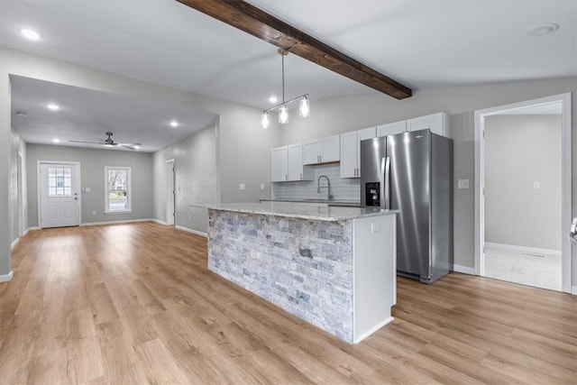 kitchen with sink, stainless steel fridge, white cabinetry, hanging light fixtures, and a center island