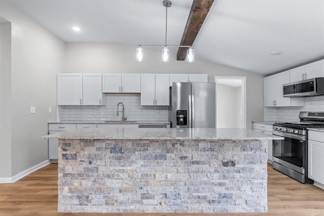 kitchen with hanging light fixtures, stainless steel appliances, a center island, light stone countertops, and white cabinets