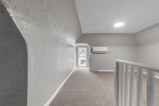 hallway featuring vaulted ceiling, a wall unit AC, and carpet