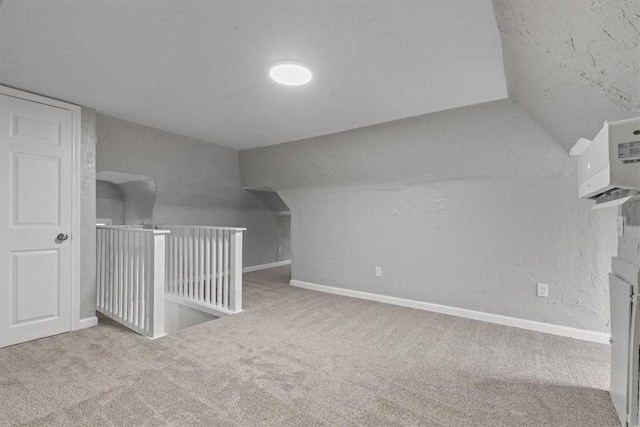 bonus room with vaulted ceiling, light carpet, and an AC wall unit