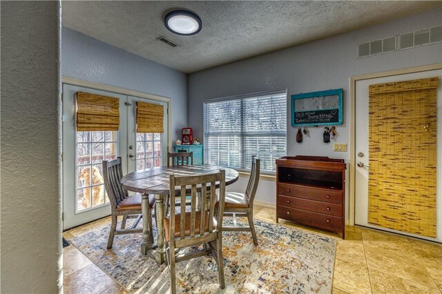 dining area featuring french doors, light tile patterned flooring, and a textured ceiling