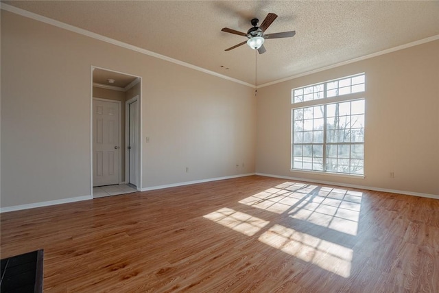 empty room featuring light wood-style flooring, a ceiling fan, a textured ceiling, baseboards, and crown molding