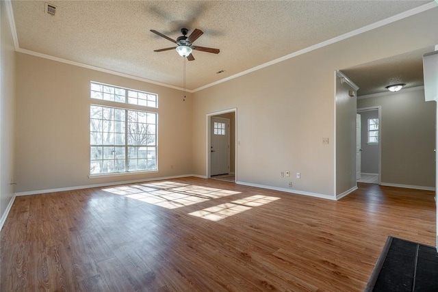 empty room featuring a ceiling fan, a textured ceiling, wood finished floors, baseboards, and ornamental molding