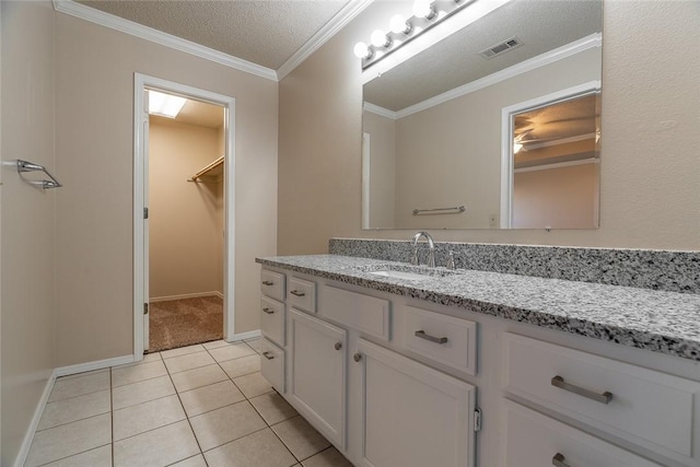 bathroom featuring tile patterned floors, vanity, a walk in closet, ornamental molding, and baseboards